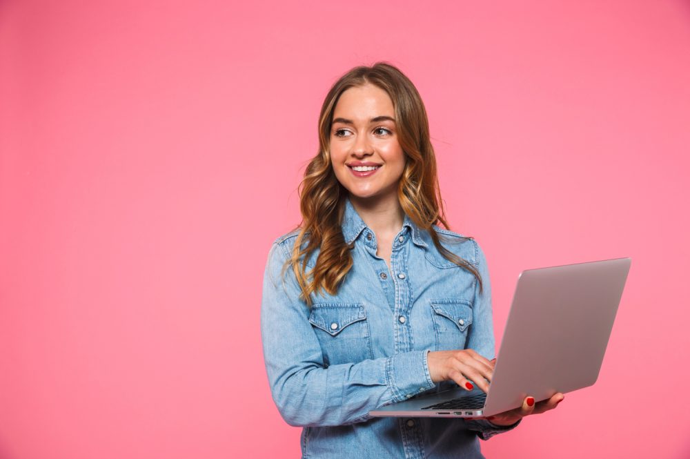 woman using a computer, pink background