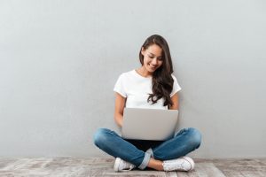 young Asian woman looking at laptop, watchin a webinar