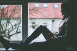 young woman looking out of window, sad, coronavirus, stress