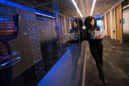 black woman working on computer in the hallway, diversity, SysAdmin Dayblack woman working on computer in the hallway, diversity, SysAdmin Day