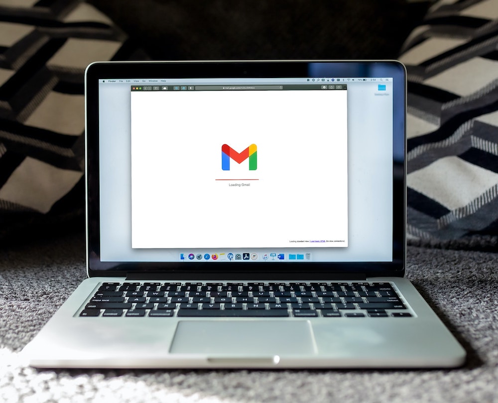 macbook pro on black background displaying Gmail, phishing emails