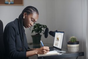 Woman working at desk, writing in a notepad, businesswoman