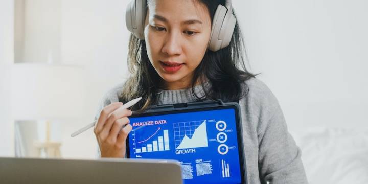 Asian businesswoman wearing headphones, analysing data working from home