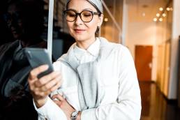 Smiling business woman standing looking at her phone
